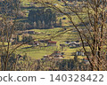 Looking trough tree branches on a village in a valley Looking trough tree branches on a village in a valley 140328422