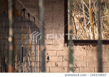 Abandoned brick wall with graffiti and barred window view Abandoned brick wall with graffiti and barred window view 140328697