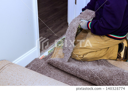 Handy man works on taking up carpet from floor in home to get ready for new flooring installation. Handy man works on taking up carpet from floor in home to get ready for new flooring installation. 140328774