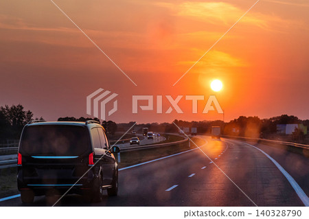 Scenic highway at sunset with minivan and cars and trucks driving through a dirty windshield. Concept of travel, transportation, freedom and the beauty of evening skies on the open road. Copy space Scenic highway at sunset with minivan and cars and trucks driving through a dirty windshield. Concept of travel, transportation, freedom and the beauty of evening skies on the open road. Copy space 140328790