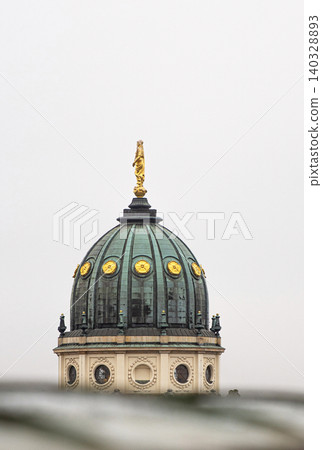 Closeup of the New German Cathedral Dome. Iconic Berlin landmark with golden statue details, seen from the French Church rooftop terrace against a soft skyline.  Minimalist photo. Copy space 140328893
