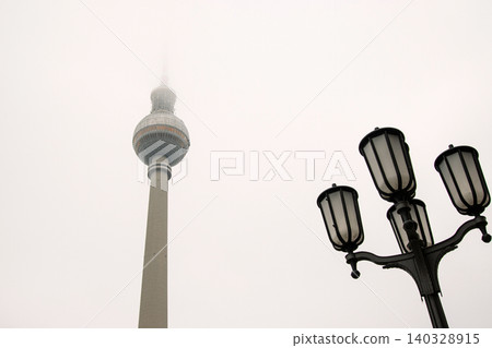 Minimalist Berlin skyline view with Berlin TV tower disappearing into fog. Foggy Fernsehturm in Berlin, Germany. Vntage street lamps in the foreground. Cloudy sky on background. Copy space Minimalist Berlin skyline view with Berlin TV tower disappearing into fog. Foggy Fernsehturm in Berlin, Germany. Vntage street lamps in the foreground. Cloudy sky on background. Copy space 140328915