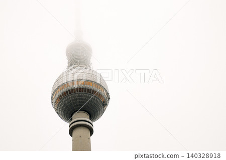 Berlin TV tower in dense fog, iconic Alexanderplatz landmark disappearing into mist. Foggy Fernsehturm in Berlin, Germany. Cloudy sky on background. Copy space 140328918