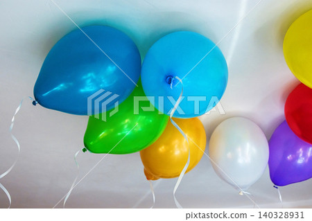 Group of multicolored vibrant helium balloons with ribbons in red, blue, yellow, green, purple, and white hanging from a ceiling, perfect for party themes or event decorations. Copy space Group of multicolored vibrant helium balloons with ribbons in red, blue, yellow, green, purple, and white hanging from a ceiling, perfect for party themes or event decorations. Copy space 140328931
