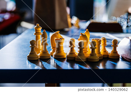 Chess pieces in sunlight on a blue tournament table after the endgame. Closeup of white chess pieces with a dramatic light effect, emphasizing intellectual depth of chess. Selective focus Chess pieces in sunlight on a blue tournament table after the endgame. Closeup of white chess pieces with a dramatic light effect, emphasizing intellectual depth of chess. Selective focus 140329062