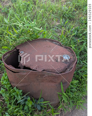 一個鏽跡斑斑的油桶被遺棄在草地上 / 廢棄的景象象徵著衰敗和環境問題。 一個鏽跡斑斑的油桶被遺棄在草地上 / 廢棄的景象象徵著衰敗和環境問題。 140329103