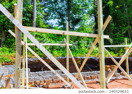 Workers set up wooden frames beams supports to shed at construction site surrounded by trees Workers set up wooden frames beams supports to shed at construction site surrounded by trees 140329631