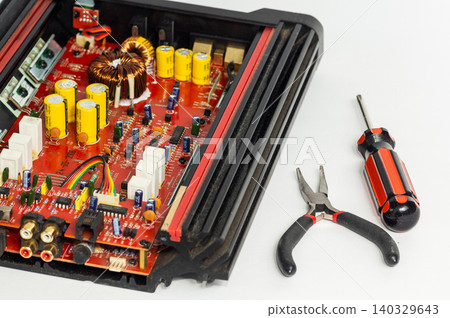 A multimeter with test probes and a circuit board lie on a white background. A multimeter with test probes and a circuit board lie on a white background. 140329643