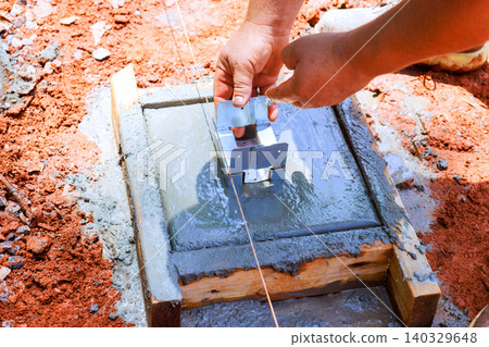Worker places metal bracket into freshly poured concrete at construction site Worker places metal bracket into freshly poured concrete at construction site 140329648