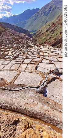 The famous historic Maras salt mines in the Andes, beneath a blue, cloudy sky, Peru 140329663