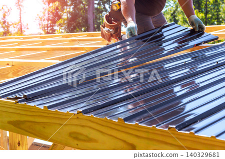 Roofer workers place metal roofing sheets on wooden joins structure in construction site Roofer workers place metal roofing sheets on wooden joins structure in construction site 140329681