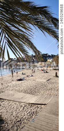 Sunny beach day with people relaxing under palm trees Sunny beach day with people relaxing under palm trees 140329688