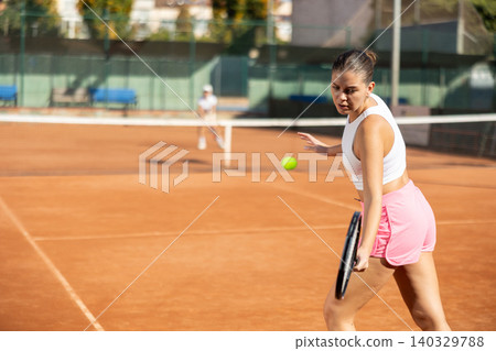 Young woman playing tennis against older woman 140329788
