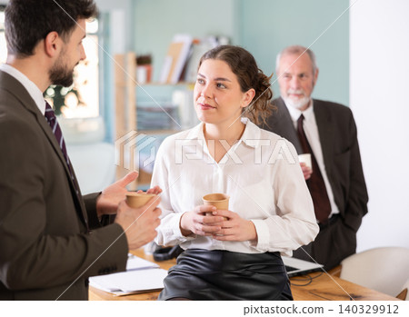 Girl with man colleagues chat and laugh during coffee break Girl with man colleagues chat and laugh during coffee break 140329912