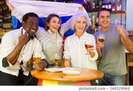 Multiracial sport supporters waving Russian flag while resting with beer in the sport bar Multiracial sport supporters waving Russian flag while resting with beer in the sport bar 140329968