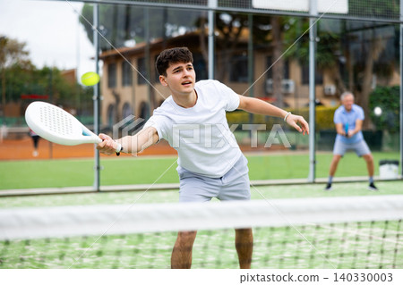 Male player ready to hits the ball while playing padel on hard court Male player ready to hits the ball while playing padel on hard court 140330003