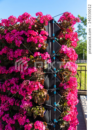 Close-up of a vertical garden tower with bright pink geranium flowers Close-up of a vertical garden tower with bright pink geranium flowers 140330012