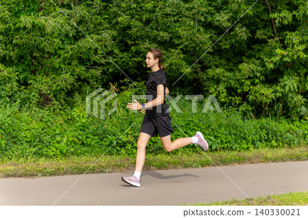 Young woman jogging on a park path Young woman jogging on a park path 140330021