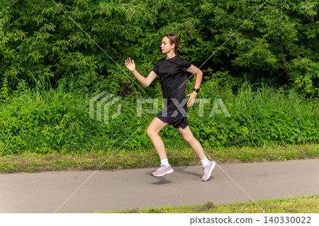 Young woman running on a park path Young woman running on a park path 140330022