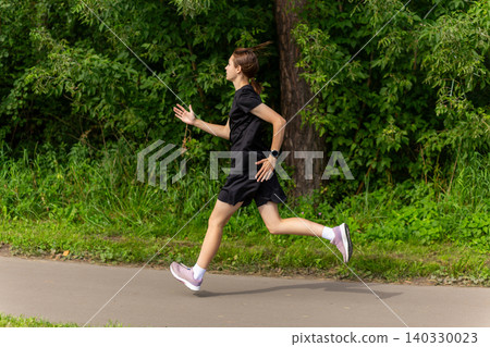 Young woman jogging on a park path Young woman jogging on a park path 140330023