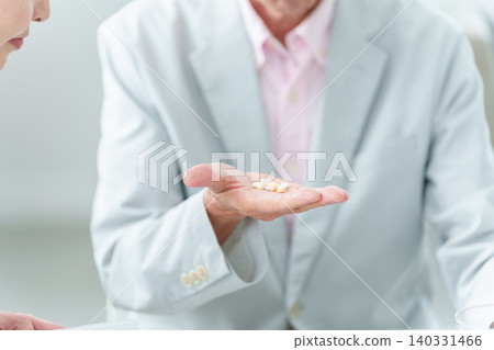 An elderly man receives an explanation about his medication from his daughter. An elderly man receives an explanation about his medication from his daughter. 140331466