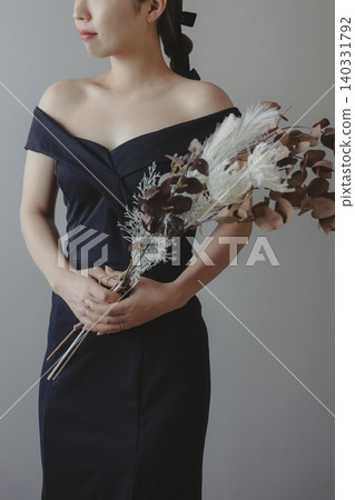 A bride in a wedding dress holding a bouquet of flowers. 140331792