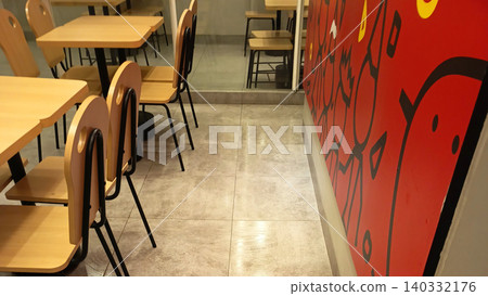 Photo of a modern cafe interior featuring an arrangement of wooden tables and chairs with a minimalist design. Photo of a modern cafe interior featuring an arrangement of wooden tables and chairs with a minimalist design. 140332176