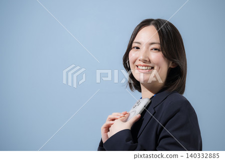一位女商人正看著鏡頭,在淺藍色背景下使用智慧型手機搜尋、尋找、查詢和查看聯絡人。 一位女商人正看著鏡頭,在淺藍色背景下使用智慧型手機搜尋、尋找、查詢和查看聯絡人。 140332885