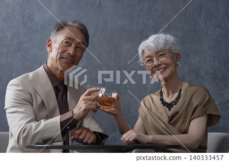 一對老年夫婦在黑色背景下喝威士忌碰杯 140333457