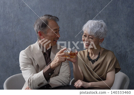 Senior couple drinking whiskey toasting black background Senior couple drinking whiskey toasting black background 140333460