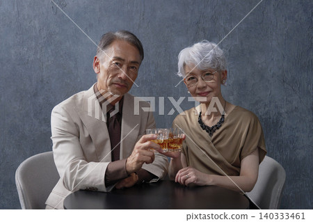 Senior couple drinking whiskey, black background, portrait, looking at camera Senior couple drinking whiskey, black background, portrait, looking at camera 140333461