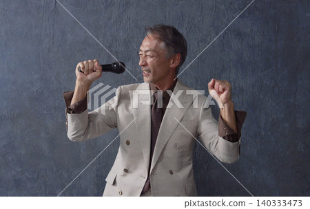 一位老人拿著麥克風在黑色背景前唱歌 140333473