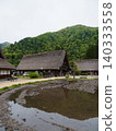 A village of thatched-roof houses nestled in the mountains 140333558