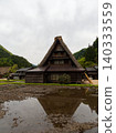 A village of thatched-roof houses nestled in the mountains 140333559