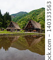 A village of thatched-roof houses nestled in the mountains 140333563