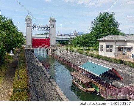 A canal scene with a sluice gate and houseboats lined up. A canal scene with a sluice gate and houseboats lined up. 140333597