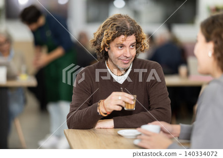 adult is sitting at a table in a cafe and talking 140334072