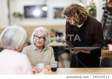 At cafe, man waiter communicates with group of customer, accepts order At cafe, man waiter communicates with group of customer, accepts order 140334113