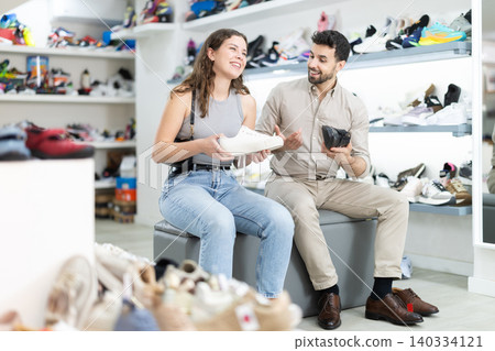 Young tries on shoes in shoe store 140334121