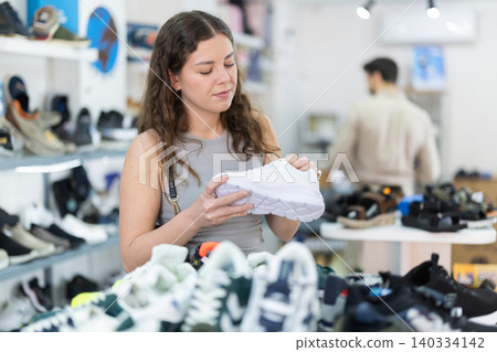 Young woman choosing sneakers in shoe store Young woman choosing sneakers in shoe store 140334142
