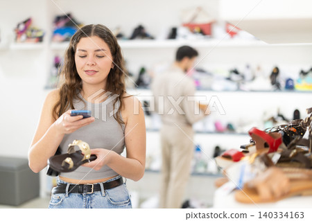 Young woman scanning barcode on sandal label in store Young woman scanning barcode on sandal label in store 140334163