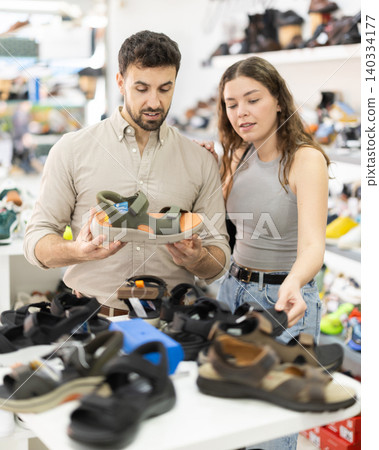 Man helps girl choose sandals Man helps girl choose sandals 140334177