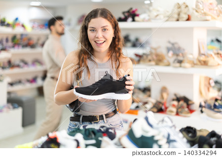 Young woman choosing sneakers in shoe store Young woman choosing sneakers in shoe store 140334294