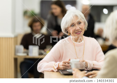 Senior female colleagues or friends are sitting in cafeteria Senior female colleagues or friends are sitting in cafeteria 140334301