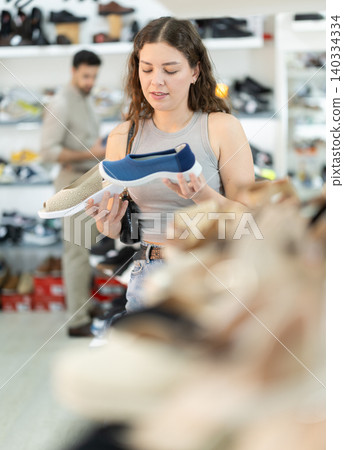 Young woman choosing sandals at footwear store Young woman choosing sandals at footwear store 140334334