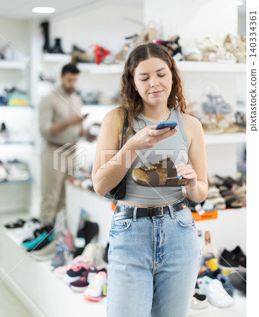 Young woman scanning barcode on sandal label in store Young woman scanning barcode on sandal label in store 140334361