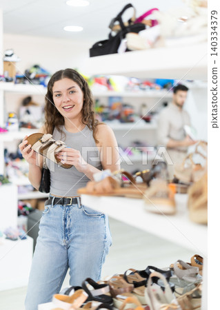 Young woman choosing sandals at footwear store Young woman choosing sandals at footwear store 140334379