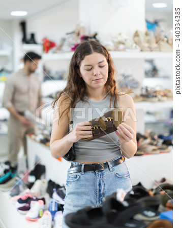 Woman choosing sandals in shoe store Woman choosing sandals in shoe store 140334385