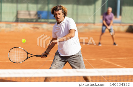 Two men in sportswear playing paddle tennis match on tennis courts, male player receiving hit from tennis racket Two men in sportswear playing paddle tennis match on tennis courts, male player receiving hit from tennis racket 140334532