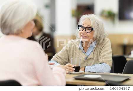 Senior female colleagues or friends are sitting in cafeteria Senior female colleagues or friends are sitting in cafeteria 140334537